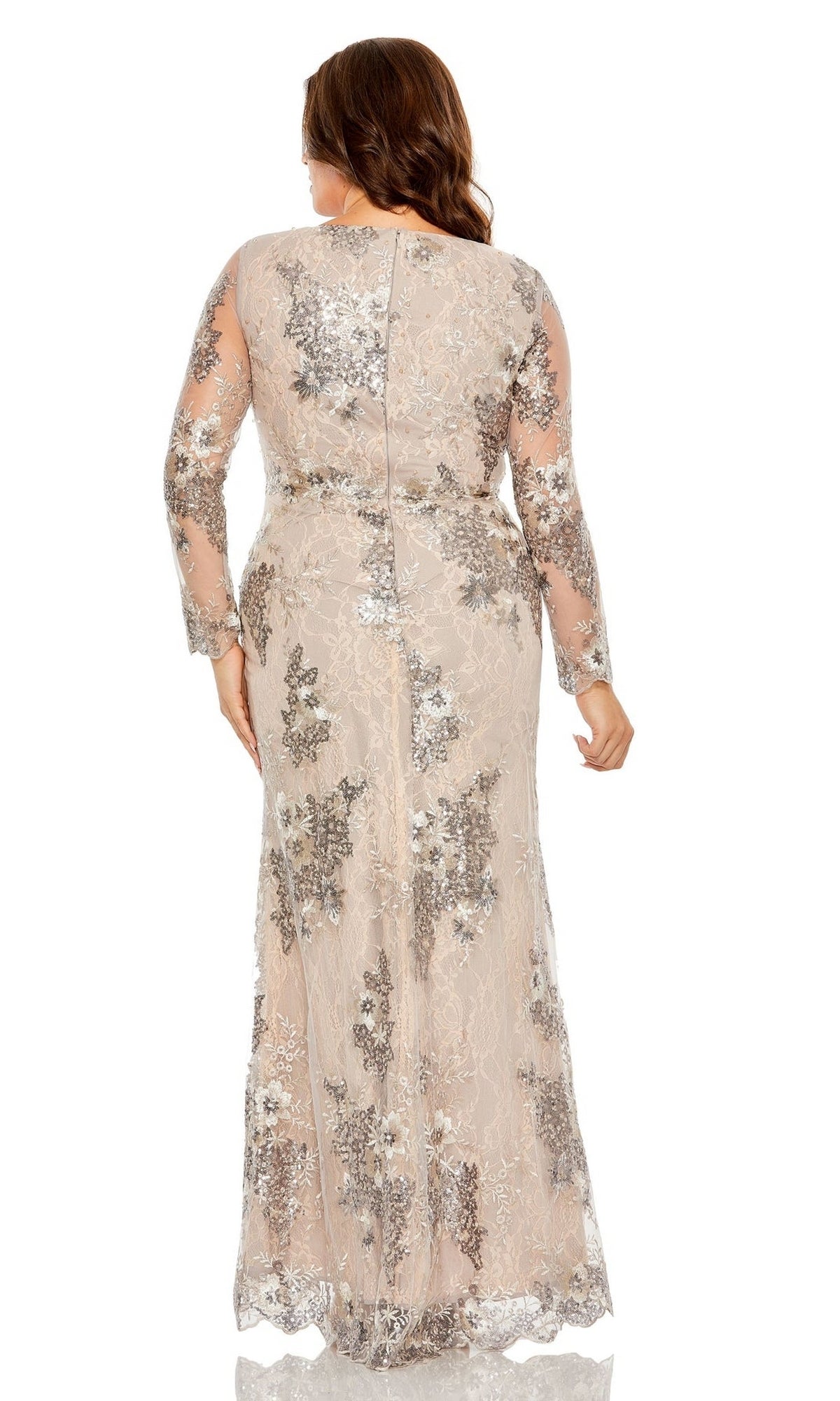A woman faces away in a plus-size, long taupe prom dress—Mac Duggal 68352—with silver floral embroidery and a sheer overlay, standing against a white background.